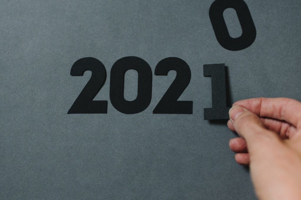 a hand writing 2021 with paper cut numbers 