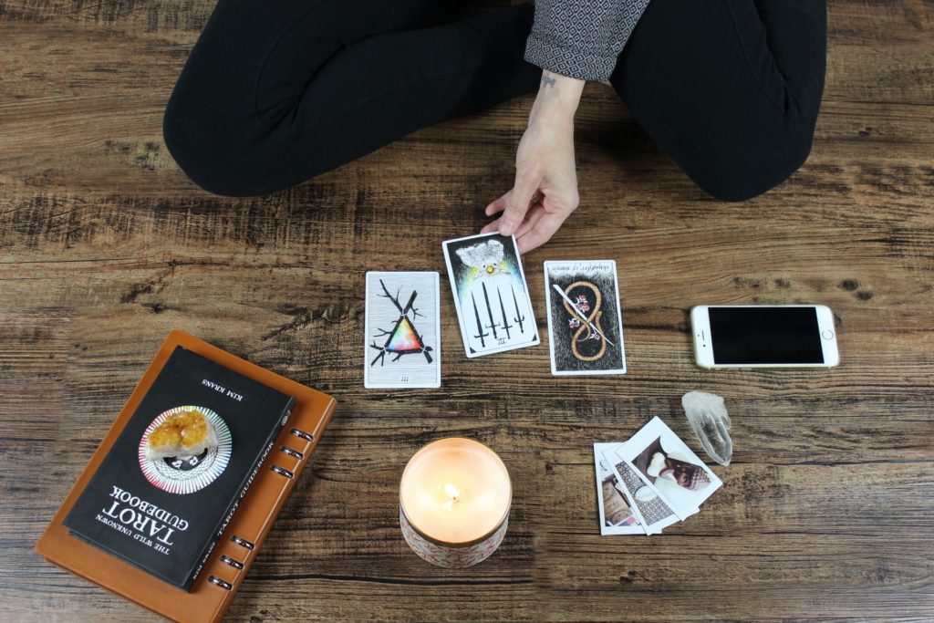 someone is playing with tarot cards on the floor with a book and a candle 