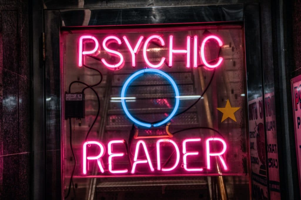 a luminous sign where is written psychic reader 