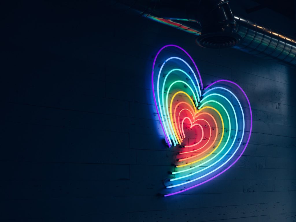 a heart-shaped illuminated sign in the colors of the rainbow