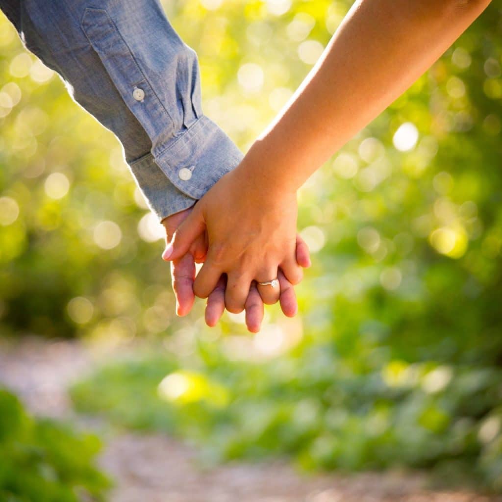 a couple hold hands in the forest
