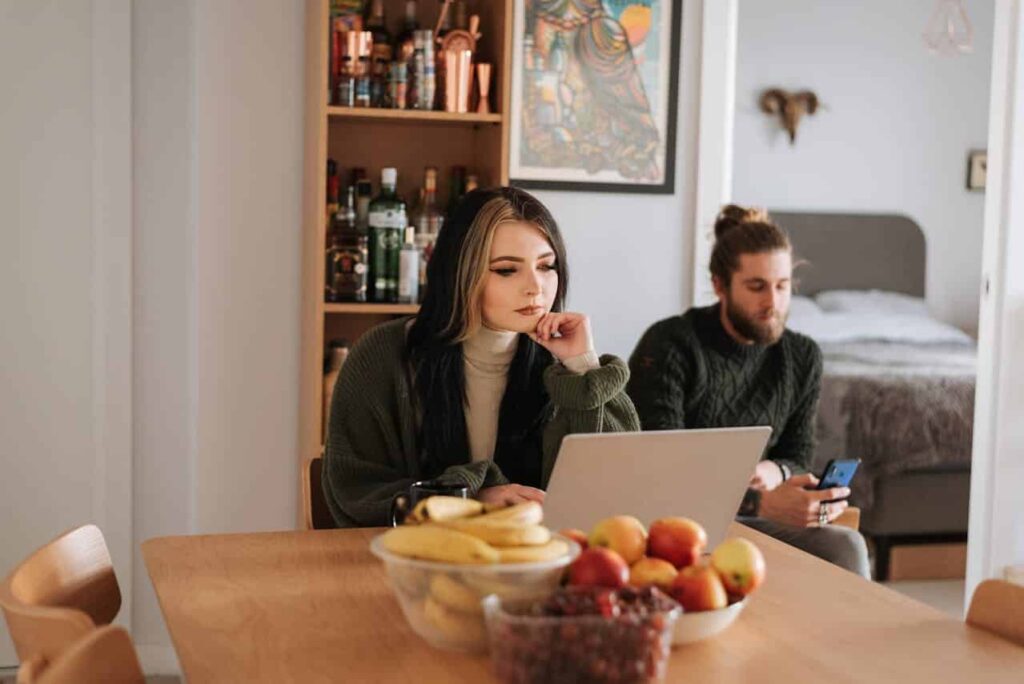 man is using a phone near a woman who is using a laptop