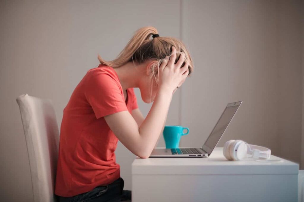 woman wearing red shirt looking at her laptop