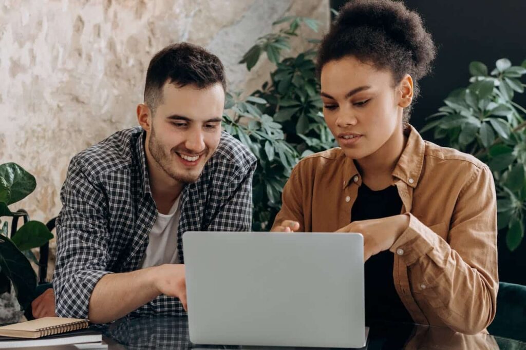 a man and a woman are watching something on a laptop