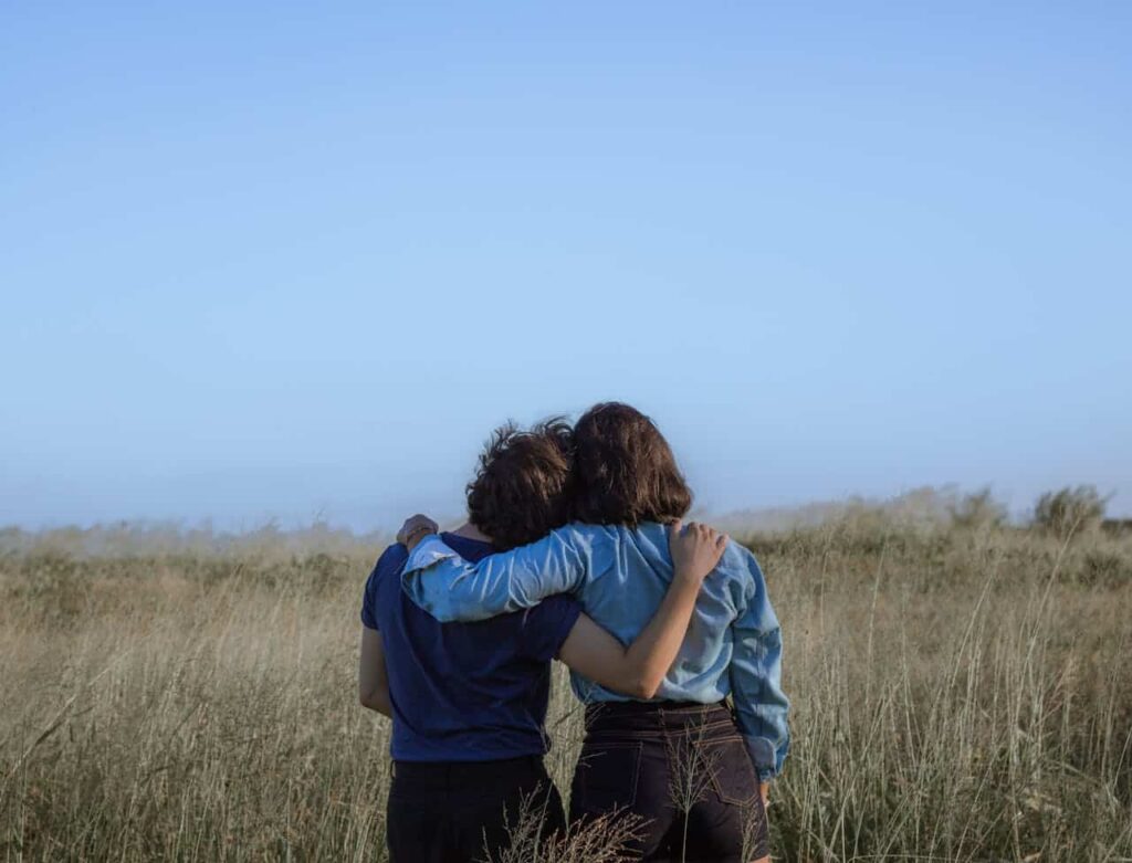 friends sharing an embrace in a spacious meadow