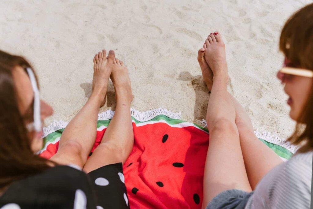 two young women sitting on white sand