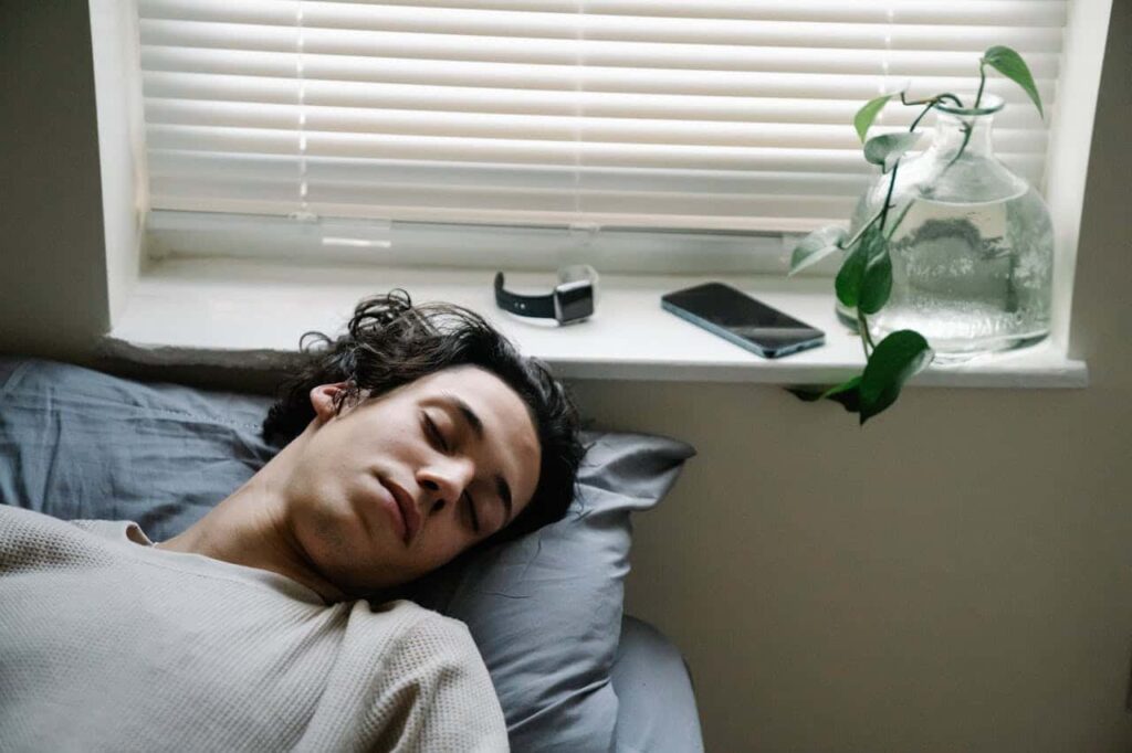 young man sleeping near gadgets