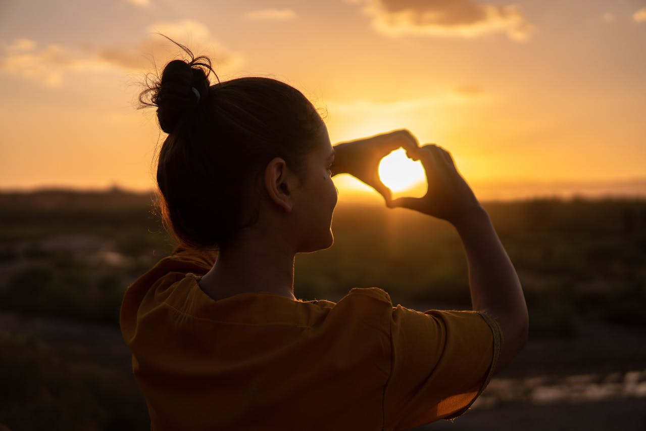 smiling woman creating heart gesture with hands