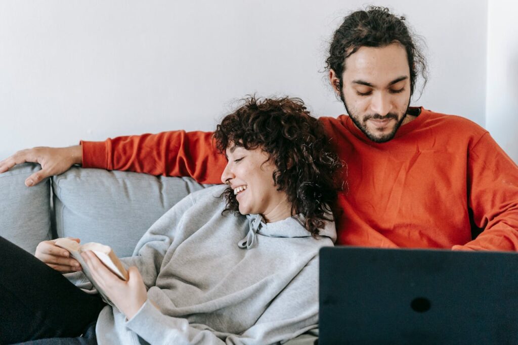a man working on a laptop while a woman reads and relaxes
