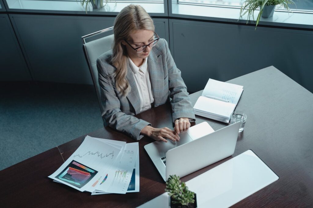 female executive in a suit, focused on working on a laptop at a desk