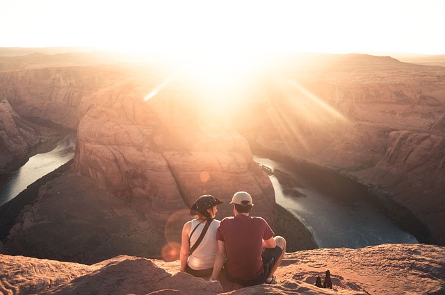 couple on a cliff watches the Grand Canyon sunrise