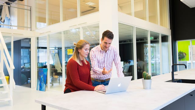 a man and a woman working together on a laptop