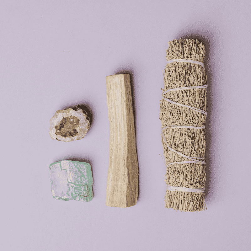 sage beside palo santo wood and crystals