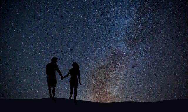 silhouettes of a couple holding hands under a starry sky