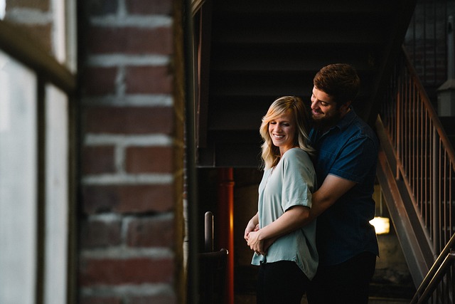 a man gently embraces a woman from behind with affection