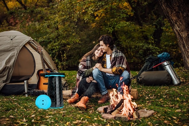 couple relaxes by a campfire in the woods