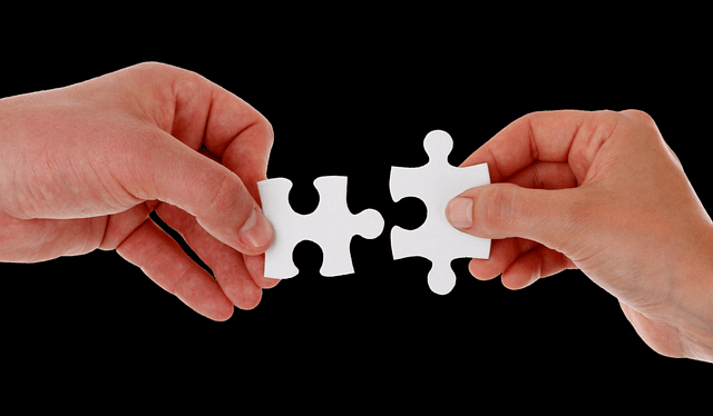 two hands connecting puzzles together