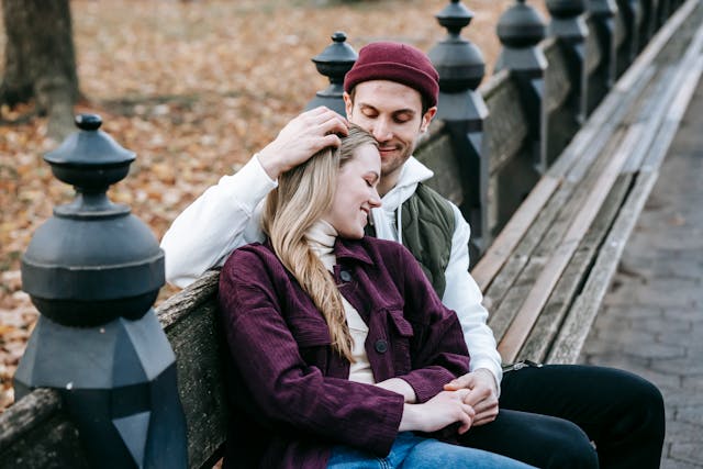 a couple cuddling on a bench in the park