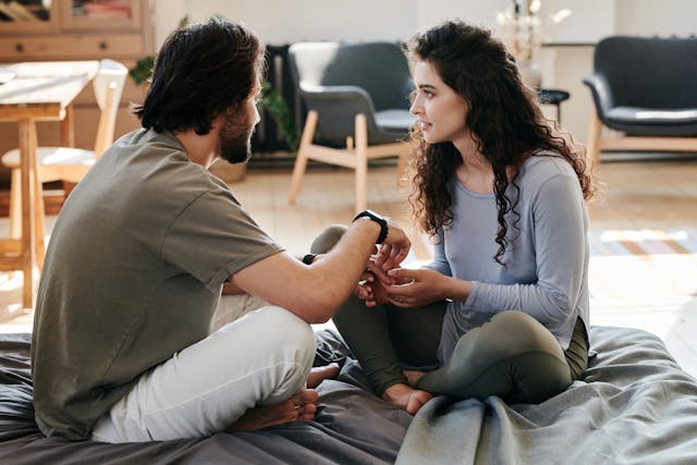 a couple is talking while sitting on the bed