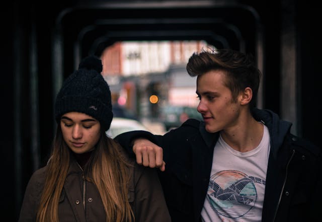 a young man staring at a young woman while comforting her
