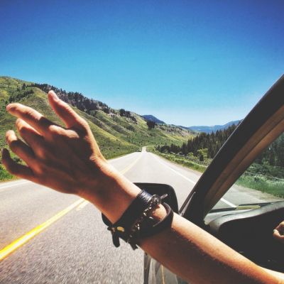 a person's hand reaches out of a car window, embodying the feeling of freedom