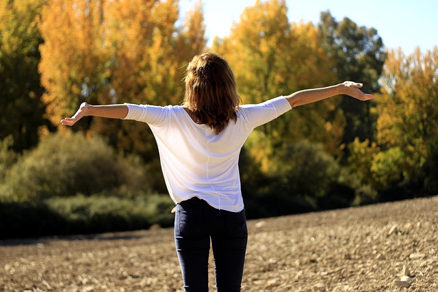 a woman stands in a field with her arms outstretched, expressing enthusiasm and optimism
