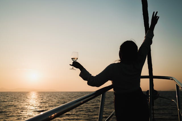 a woman enjoying a sail, glass in hand, celebrating success