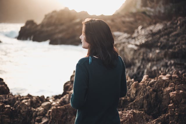 a woman standing near rock formations, enjoying the view