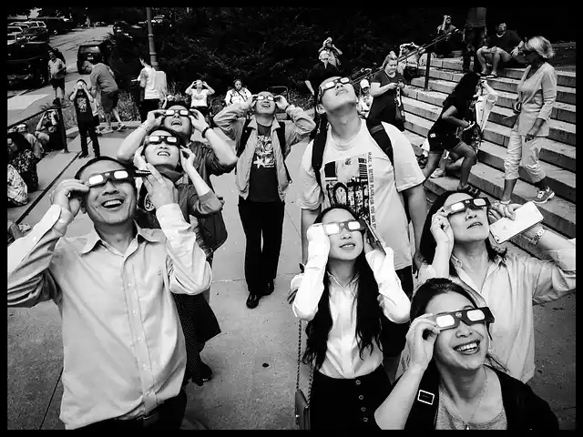 a group in solar eclipse glasses gazes at the sky