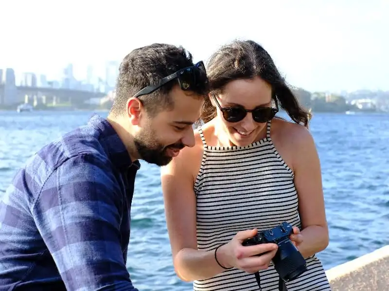 Man and woman smiling while looking at a digital camera screen | Trusted Astrology